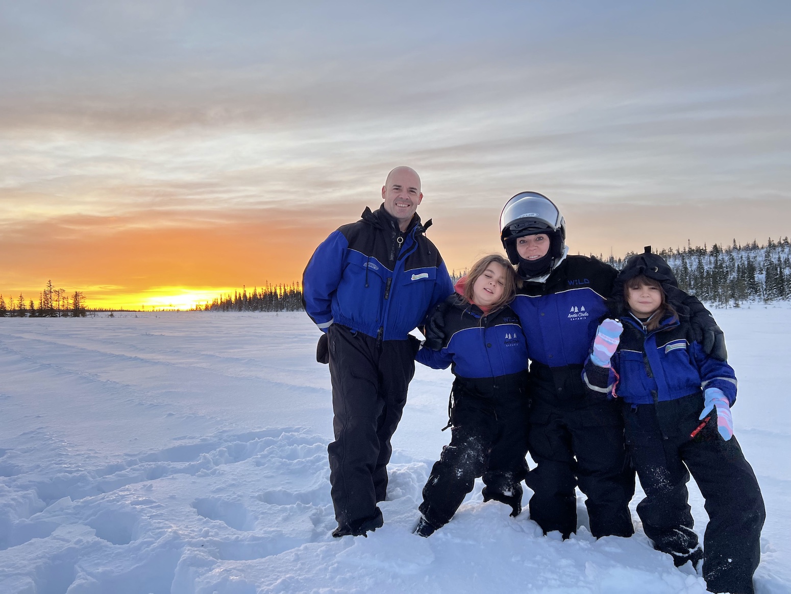 A family in winter gear at sunset in Finnish Lapland